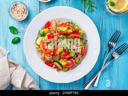 Fresh salad with vegetables, quinoa and fresh herbs on a blue background. Top view, close-up. Stock Photo