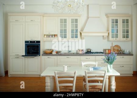 Spacious bright kitchen with a dining table in the center of the room. Stock Photo
