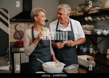 caucasian smiling elderly couple cooking in kitchen Stock Photo