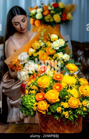 Three bouquets of flowers and in the background a girl on a sofa. Stock Photo