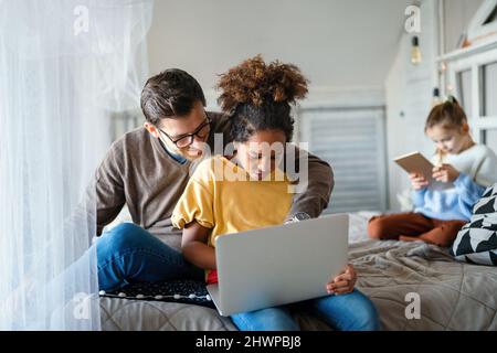Preteen schoolgirl doing her homework with notebook at home. Child using gadgets to study. Stock Photo