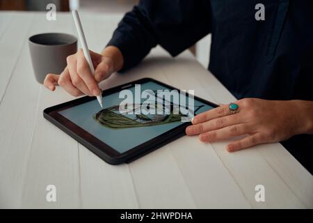 Caucasian female designer working from home creating art on digital tablet Stock Photo