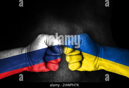 Russia And Ukraine War Crisis, Fists with flags painted, Two enemy countries fighting with each other, conflict concept isolated on black background, Stock Photo