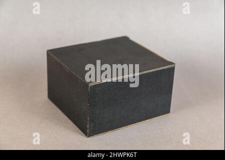 Rectangular black box on a gray background. Closed cardboard package with correct geometric shape. Stock Photo