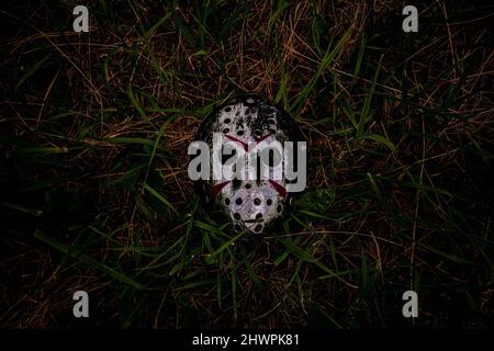 Metallic color creepy plastic hockey mask lays on ground Stock Photo