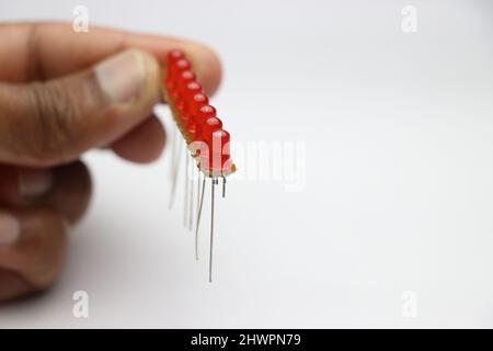 Red LED on an empty circuit board arranged in parallel circuit connection. Young inventor working on some LED project Stock Photo