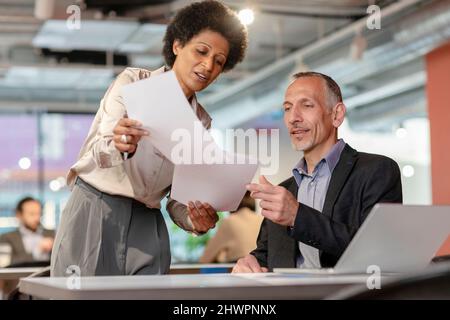 Businessman discussing with colleague over documents in coworking space Stock Photo