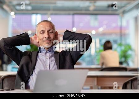 Businessman with hands behind head relaxing in office Stock Photo