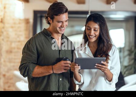 Smiling businesswoman showing tablet PC to colleague in coworking office Stock Photo