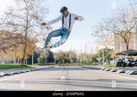 Carefree young man jumping over road in city Stock Photo