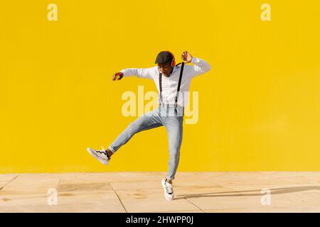 Carefree young man listening music and dancing on footpath Stock Photo
