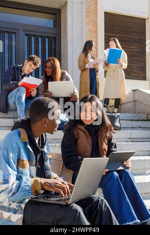 Multiracial college students studying on steps on campus Stock Photo