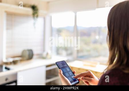 Young woman using smart home application at home Stock Photo