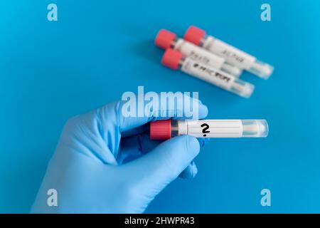 Doctor holding swab tube against blue background in studio Stock Photo