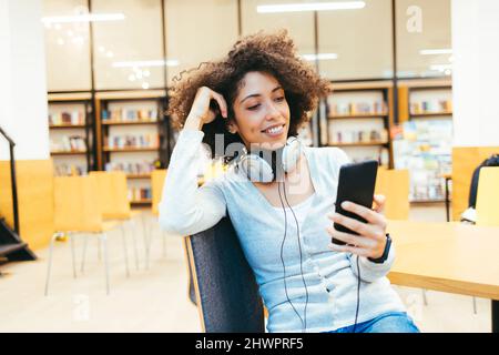 Woman with headphones around her neck using smart phone Stock Photo