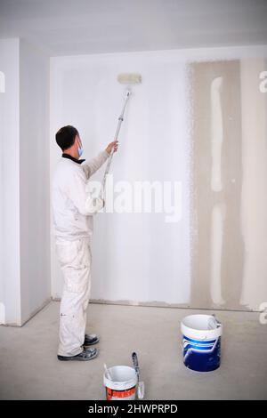 House painter painting wall with roller at construction site Stock Photo