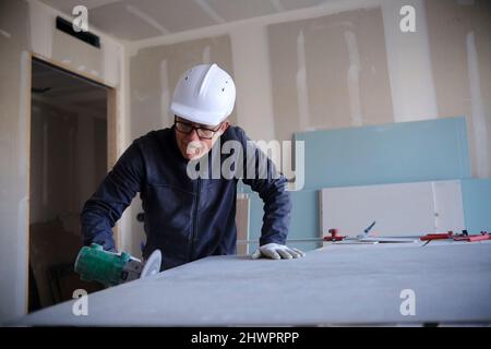 Concentrated worker with power tool at construction site Stock Photo