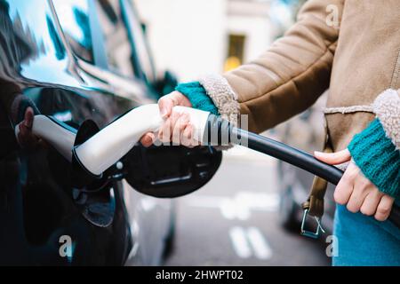 Woman charging electric car at station Stock Photo