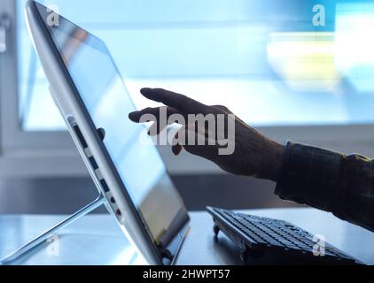 Hand of technician using tablet PC with keyboard at home office Stock Photo