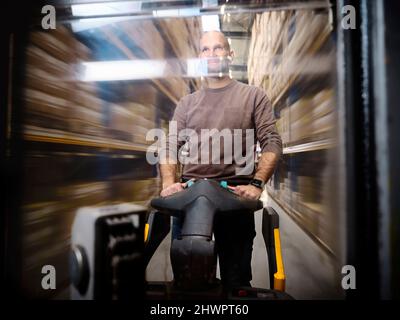 Warehouse worker pushing hand truck in alley Stock Photo