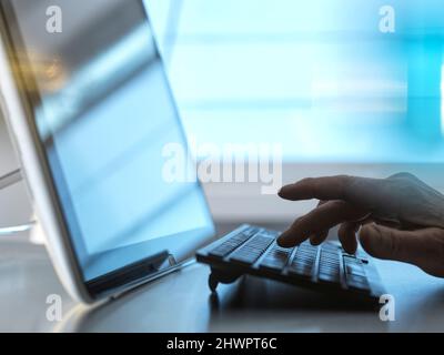 Hand of engineer typing on keyboard by tablet PC at desk in home office Stock Photo