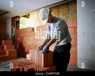 Bricklayer marking on bricks working at construction site Stock Photo