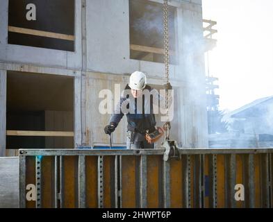 Worker holding chain attached with construction material at site Stock Photo