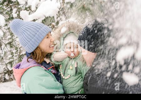 Woman carrying daughter by man playing with snow in winter Stock Photo