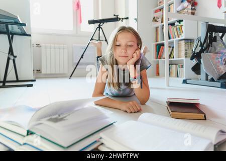 Girl looking at books lying on floor at home Stock Photo