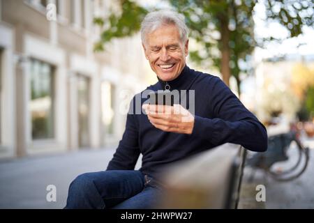 Happy senior man using smart phone in park Stock Photo