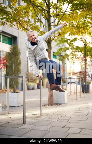 Cheerful senior man jumping on footpath Stock Photo