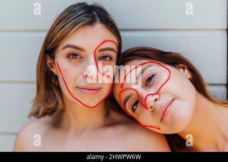 Young women with thread on face in front wall Stock Photo