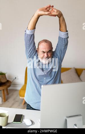 Tired businessman stretching hands in home office Stock Photo