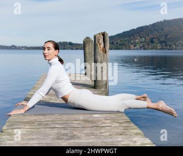 Active woman doing cobra pose on jetty Stock Photo
