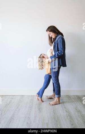 Pregnant mother with daughter standing by wall Stock Photo