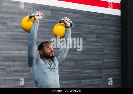 Determined sportsman lifting kettlebell in gym Stock Photo