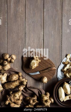 Jerusalem Artichoke and knife on chopping board on wooden table Stock Photo