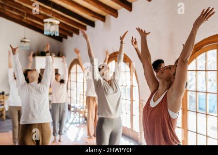 Yoga instructor teaching exercise to students in class Stock Photo
