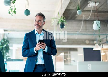 Smiling businessman using mobile phone at workplace Stock Photo