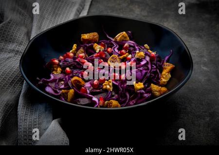 Studio shot of bowl of vegan salad with red cabbage, pomegranate seeds, dried figs and walnuts Stock Photo
