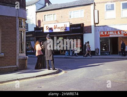 Female secondary school students with clipboards doing geography fieldwork, West Street, Leominster, Herefordshire, England, UK 1970s girls conducting questionnaires interviewing a policeman 1975 Stock Photo