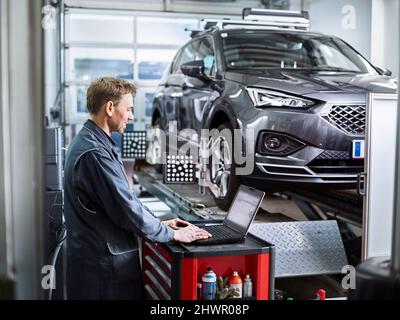 Car mechanic using laptop at auto repair shop Stock Photo