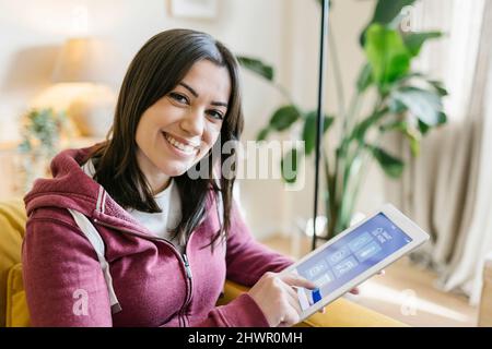 Smiling woman using tablet PC to control smart home Stock Photo