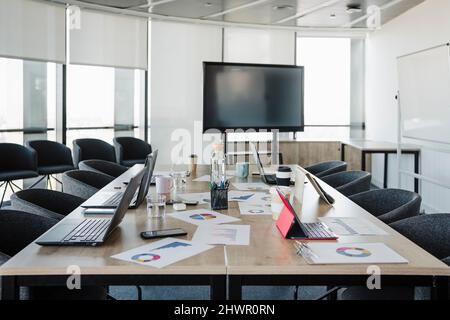 Laptops and graphs kept on conference table in empty meeting room Stock Photo