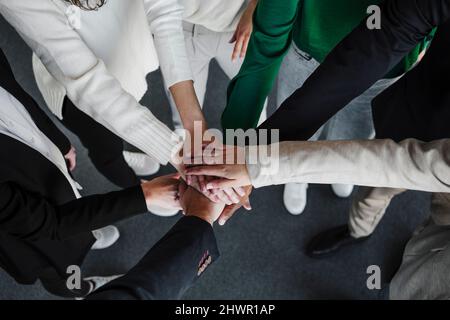 Businesswomen and businessmen stacking hands in office Stock Photo