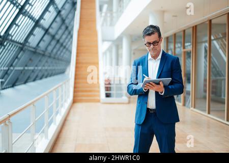 Businessman using tablet PC standing at office Stock Photo
