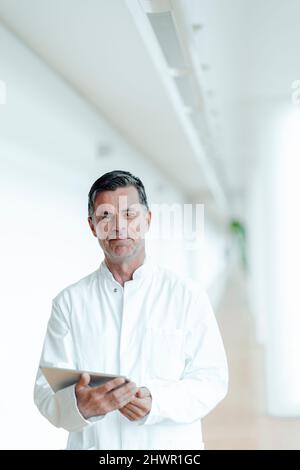 Smiling scientist with tablet PC standing at medical clinic Stock Photo