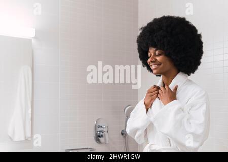 Smiling young woman wearing bathrobe in bathroom Stock Photo