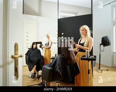 Hairdresser styling customer's hair in salon Stock Photo