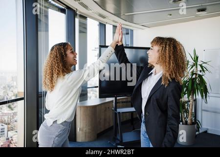 Businesswomen giving high-five to each other at office Stock Photo